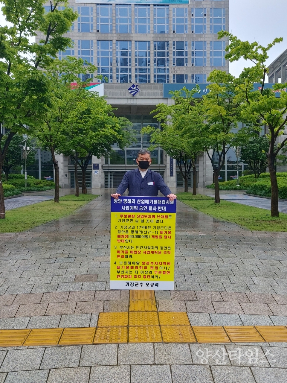 "토요일인 12일 오전11시 기장군수가 부산시청 앞에서 장안읍 명례리 산업폐기물 매립시설 사업계획 승인 결사반대를 외치며 빗속에서 1인 시위 중이다."ⓒ양산타임스
